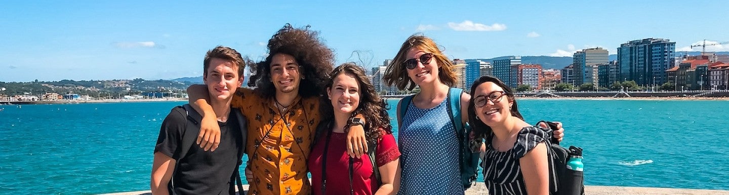Group of UO students posing in front of a body of water with a city skyline in the background
