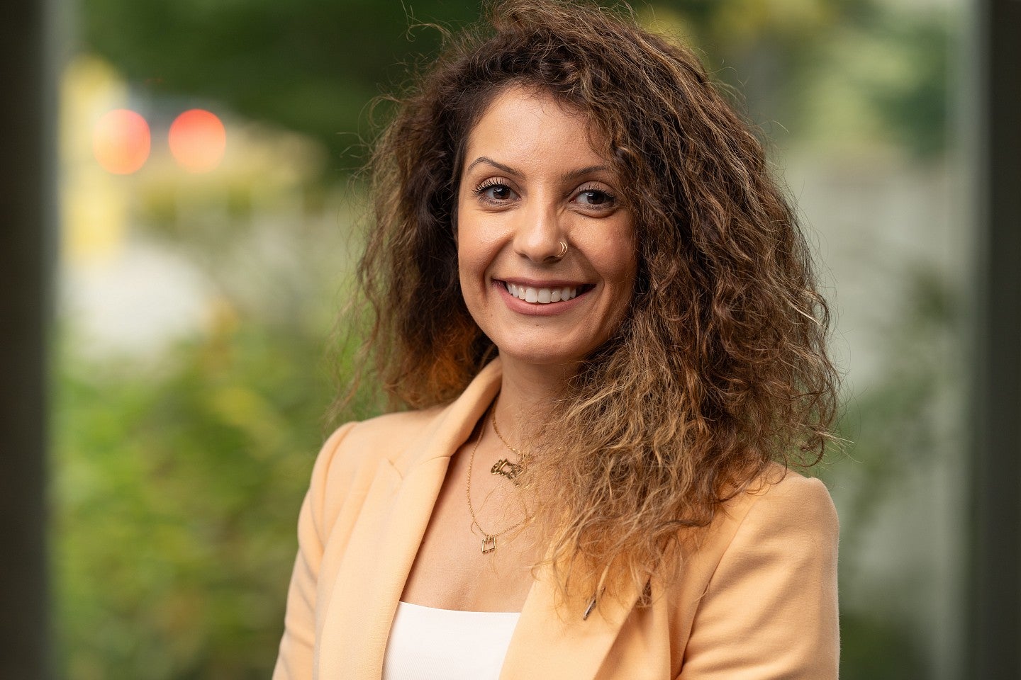 Headshot of Hadil Abuhmaid standing in front of greenery