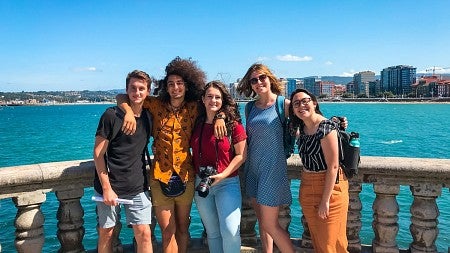 Group of UO students posing in front of a body of water with a city skyline in the background
