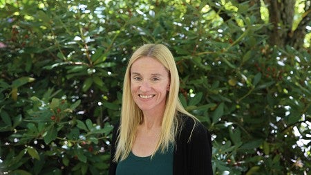 Krista Farris headshot standing in front of greenery