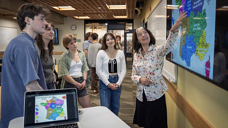 university professor pointing to a map on a screen with students observing