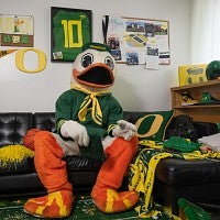 The Oregon Duck mascot sitting in an apartment decorated with University of Oregon gear